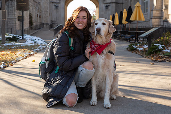 Student poses with service dog in front of Memorial Union