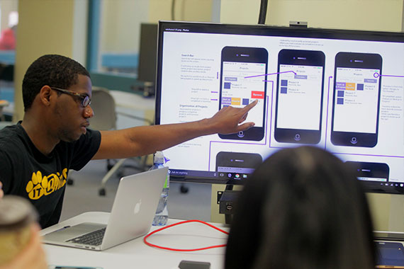 Student pointing to mobile phone app mock-ups on screen