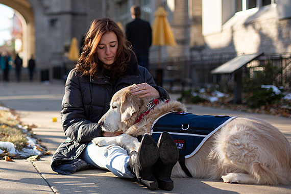 Sophie Endacott sitting on sidewalk with service dog