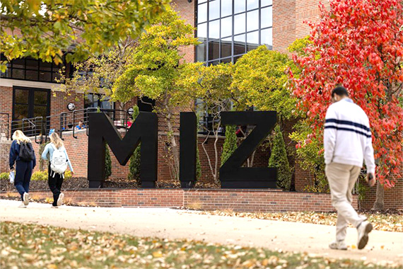 People walk near M I Z statue