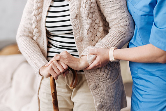 Nurse assists woman with cane