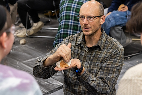 Professor holds tool in hand and shows to students