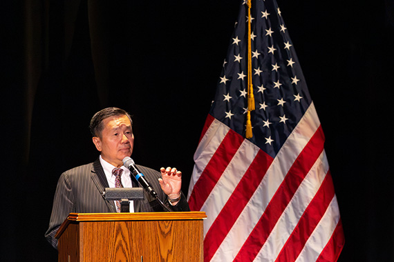 Mizzou president Mun Choi speaking at a podium in front of American flag