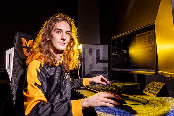 Jasper Holland sitting at a computer with one hand on keyboard and one hand on mouse