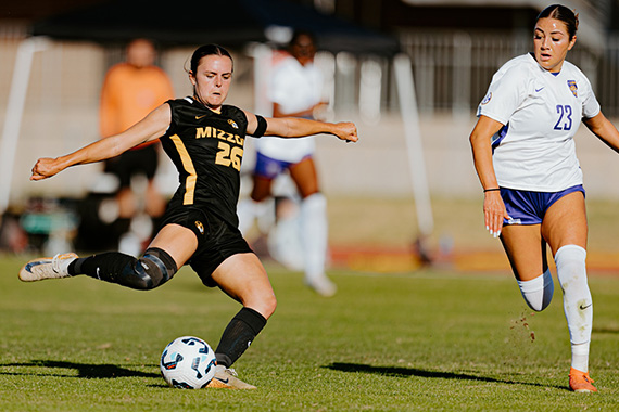 A Mizzou Tiger soccer player in mid-kick as a defender approaches