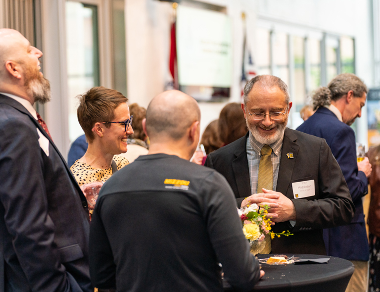 Members of faculty standing around a table laughing