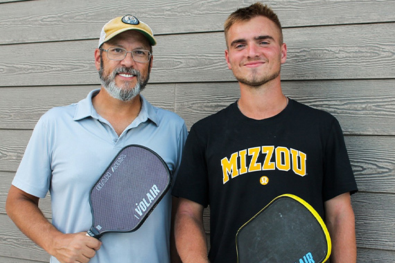 Two people holding pickleball paddles