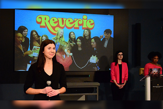 Student holding a microphone standing in front of a large screen